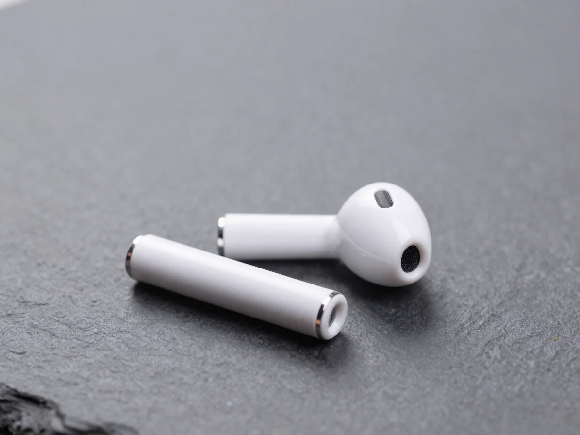 Isolated product close-up of wireless earbuds on a matte slate background, crisp shadows, 50mm macro lens